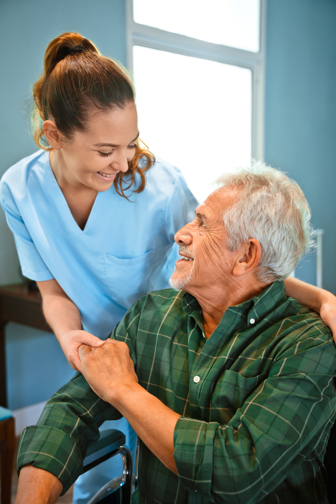 Smiling nurse holding hands of disabled man